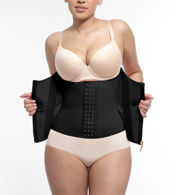 Woman wearing a black waist trainer with beige bra and underwear on a white background